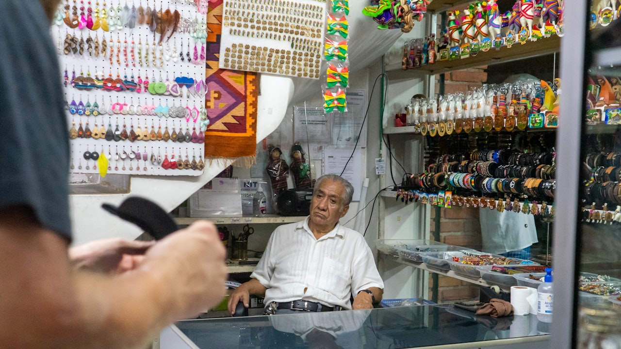 Dueño de un comercio chico atendiendo en su mostrador