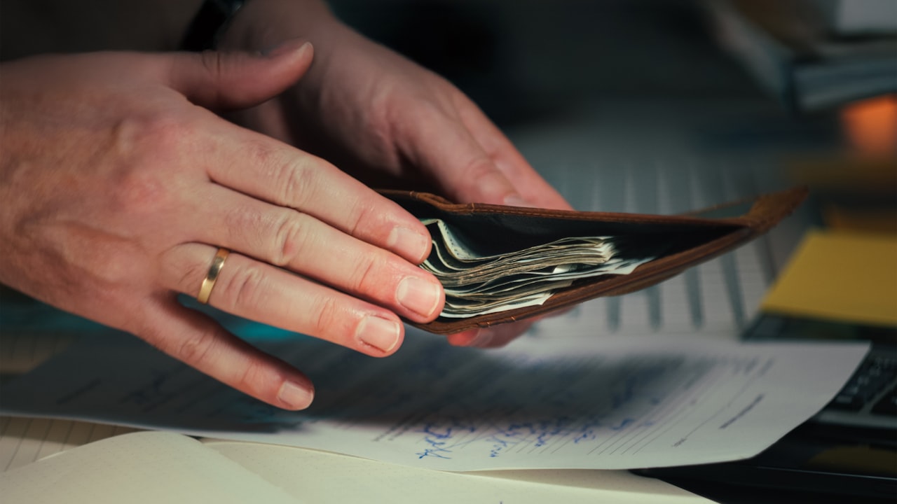 Mano pagando en efectivo sobre facturas en un escritorio