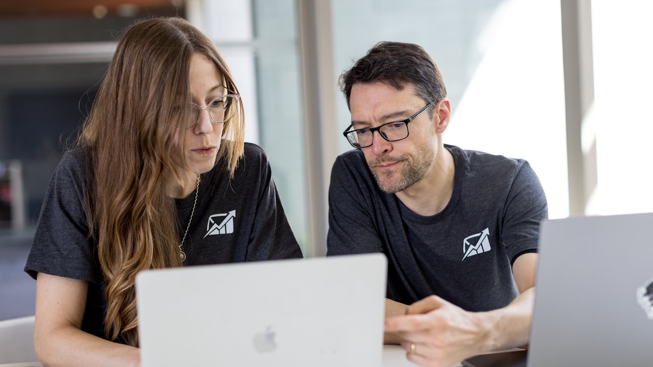 Dos compañeros consultando juntos la misma información en una laptop