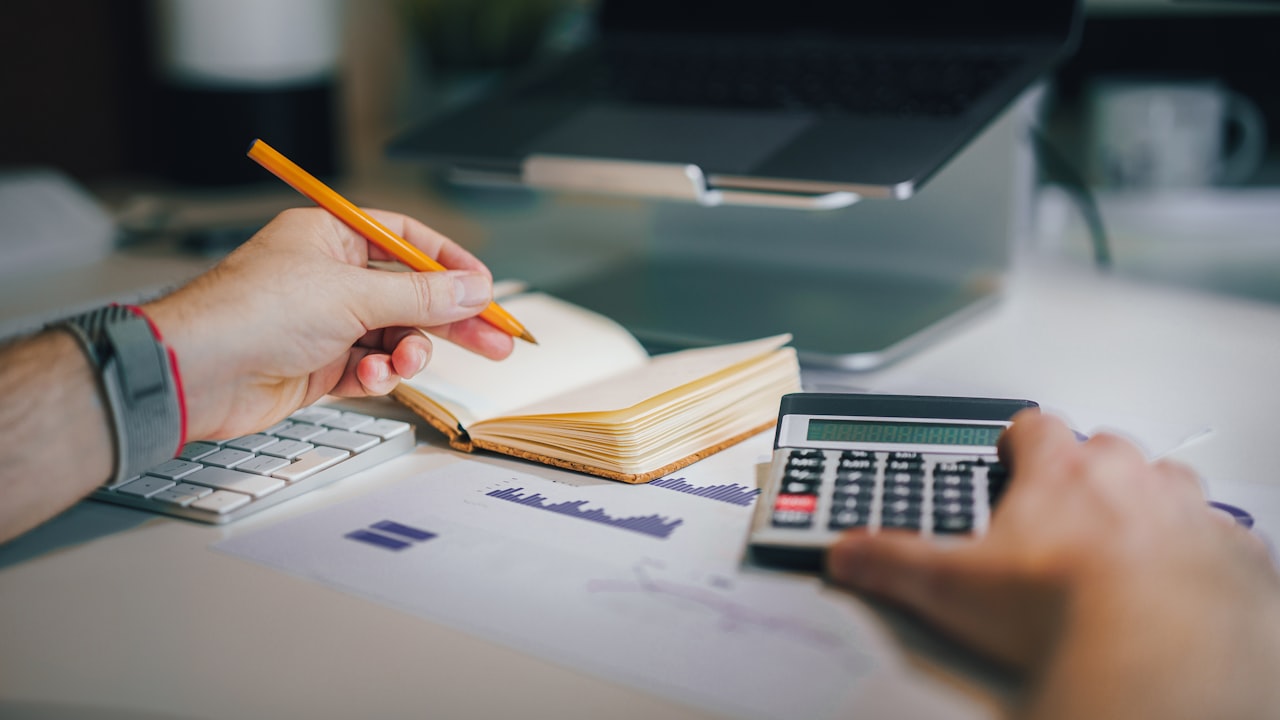 Calculadora, anotador y números sobre el escritorio