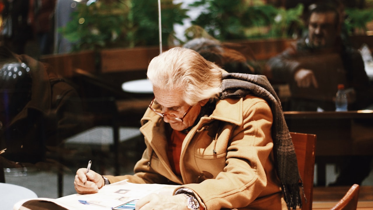 Comerciante de más edad anotando a mano en un cuaderno sobre el mostrador