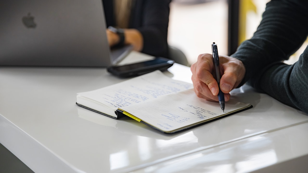 Persona planificando un flujo de trabajo con notas sobre la mesa