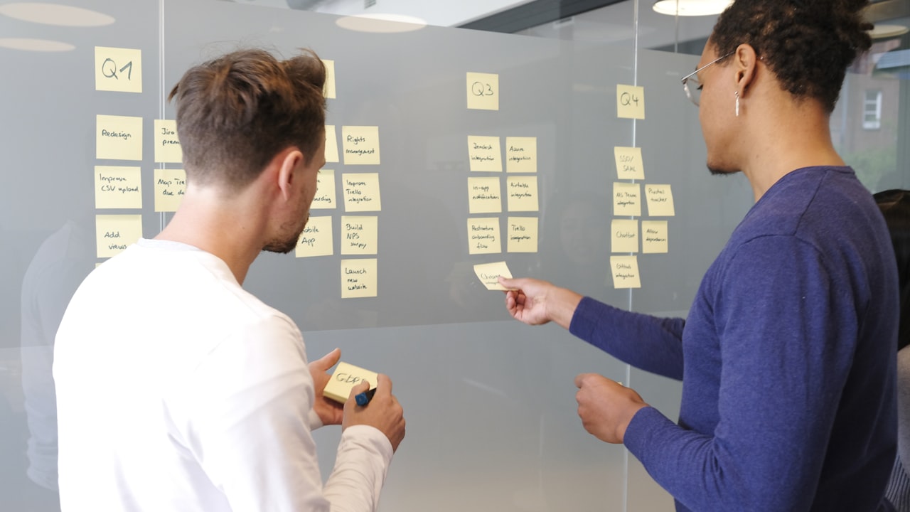 Persona reacomodando notas adhesivas en un tablero de planificación